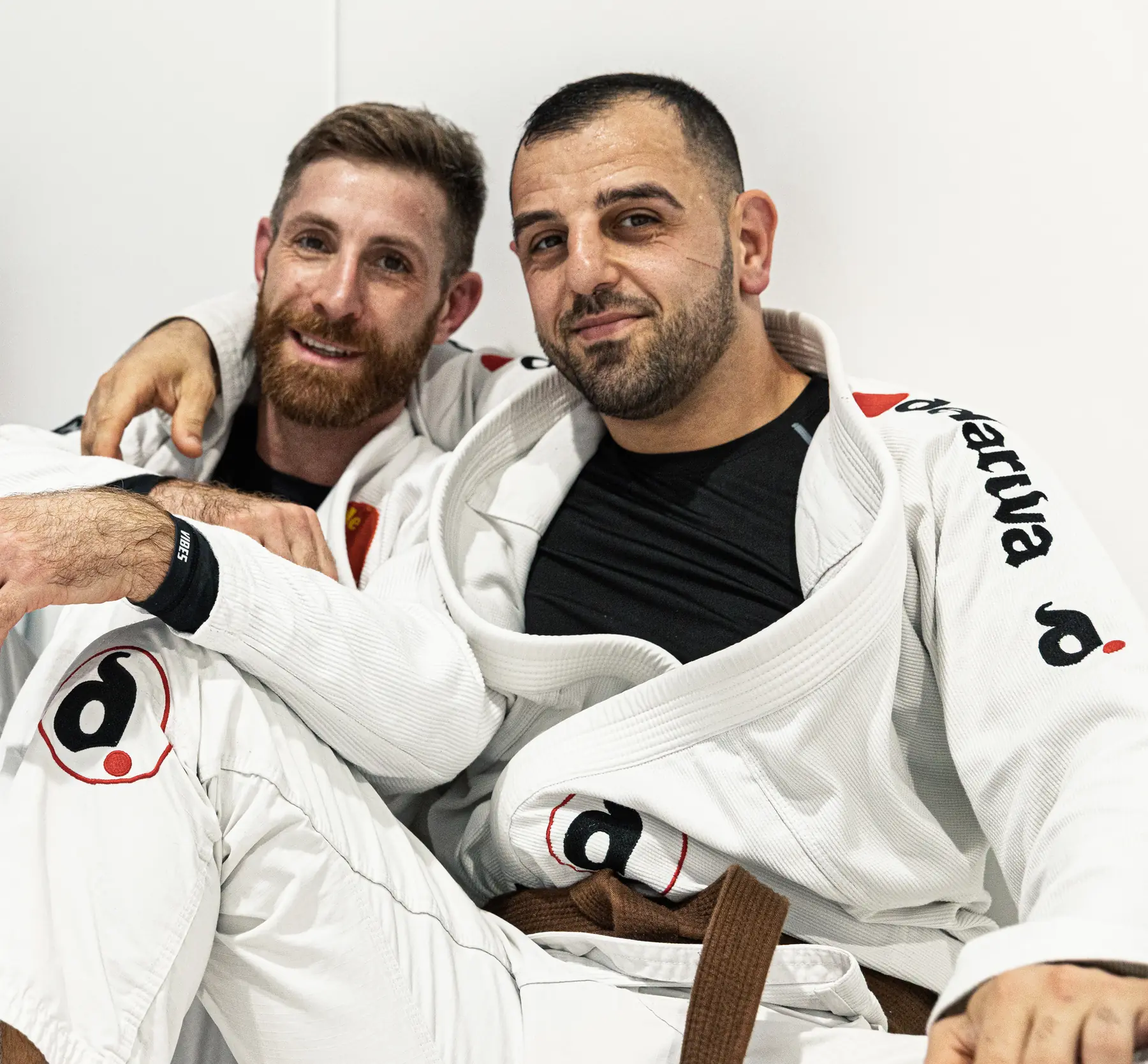 Zwei Trainingspartner sitzen entspannt nebeneinander im Gi.