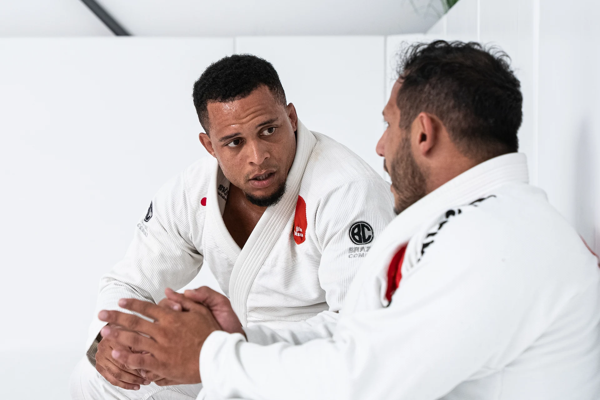 Zwei Trainingspartner im weißen Gi besprechen eine Technik.