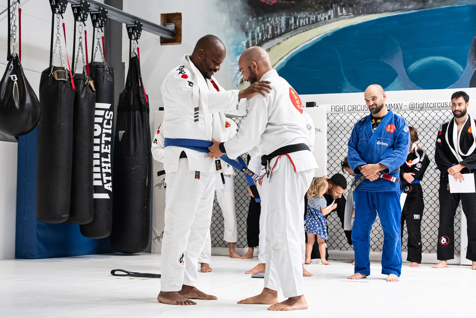 Ein BJJ-Praktizierender erhält im Kreis der Trainingsgemeinschaft einen blauen Gürtel.